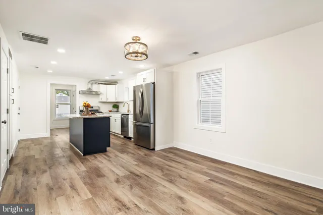 a kitchen with stainless steel appliances kitchen island granite countertop a refrigerator and a stove top oven