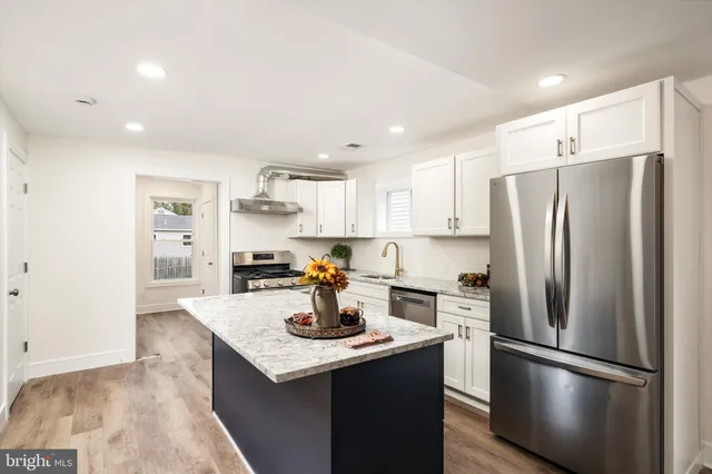 a kitchen with a refrigerator a sink and a stove top oven with wooden floor
