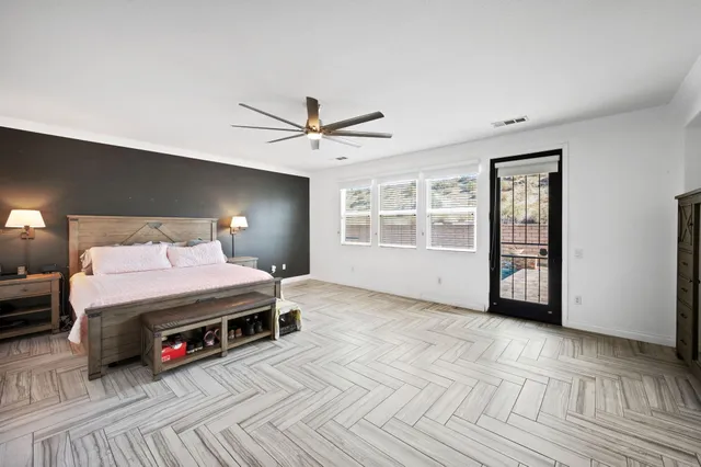 a spacious bedroom with a bed a dresser and window