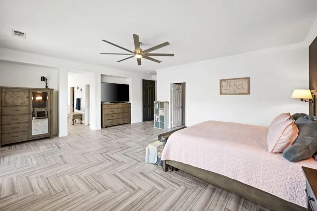 a bedroom with a large bed a flat tv screen and dresser