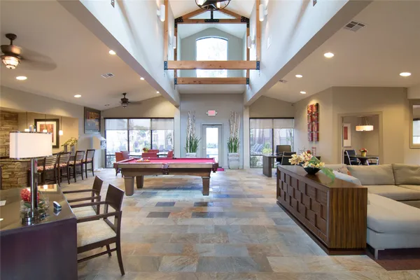 a living room with lots of furniture kitchen view and a large window