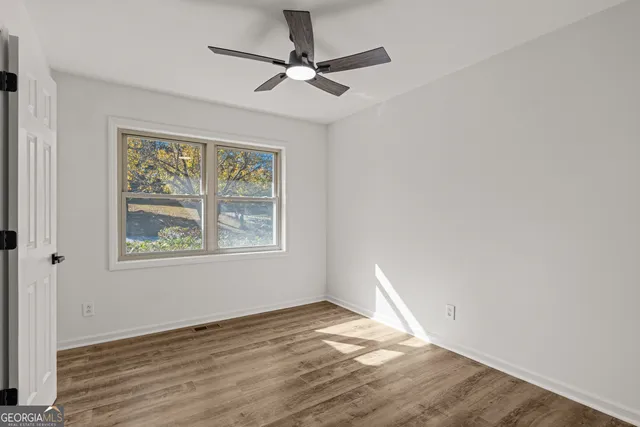 a view of empty room with wooden floor and fan