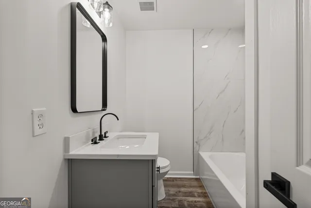 a bathroom with a sink and mirror with bathtub