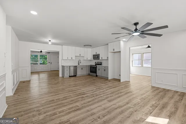 a view of an empty room with a kitchen and wooden floor