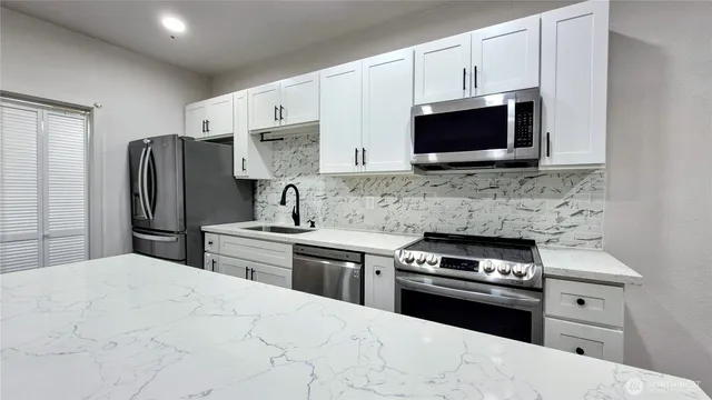 a kitchen with stainless steel appliances a stove microwave and sink