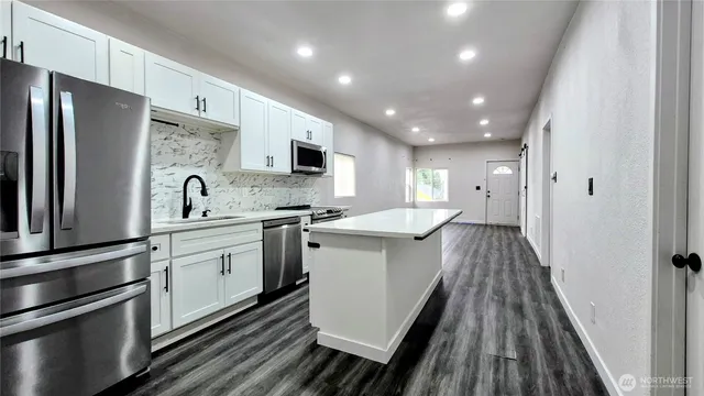 a kitchen with refrigerator a sink and wooden floor