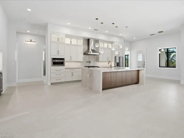 a large kitchen with stainless steel appliances lots of white cabinets