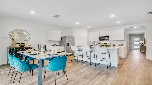 a kitchen with stainless steel appliances kitchen island granite countertop a table chairs and a refrigerator