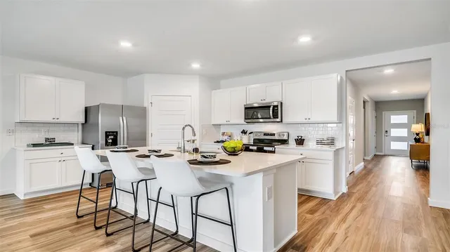 a kitchen with white cabinets appliances and wooden floor