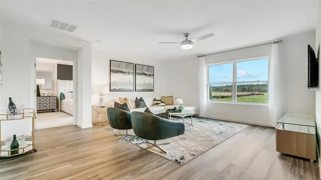 a living room with furniture a window and wooden floor