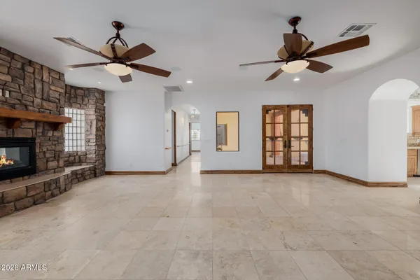 a view of an empty room with window and kitchen view