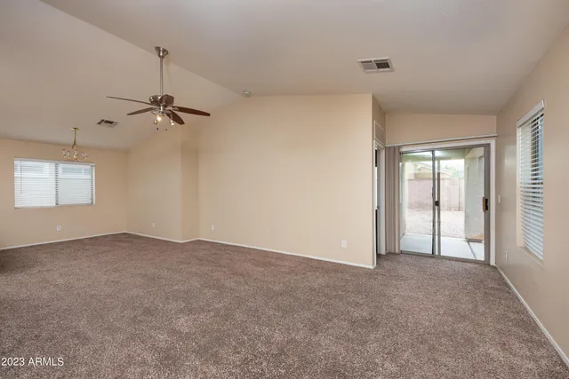 an empty room with windows and ceiling fan