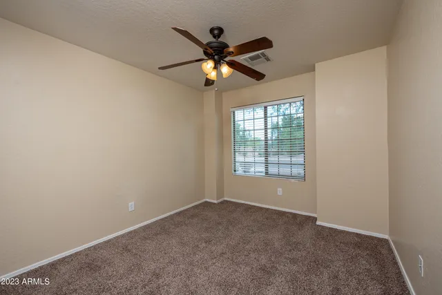 an empty room with a window and a fan
