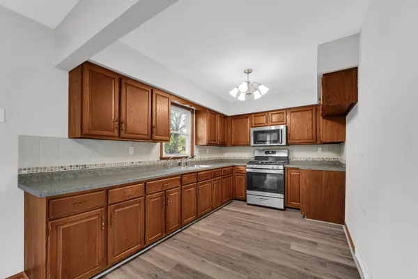 a kitchen with stainless steel appliances granite countertop wooden cabinets a stove top oven a sink and dishwasher