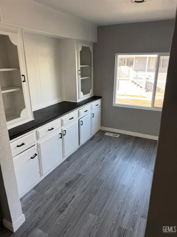 a large white kitchen with sink and wooden floor