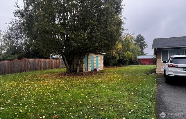 a view of house with a big yard and large trees