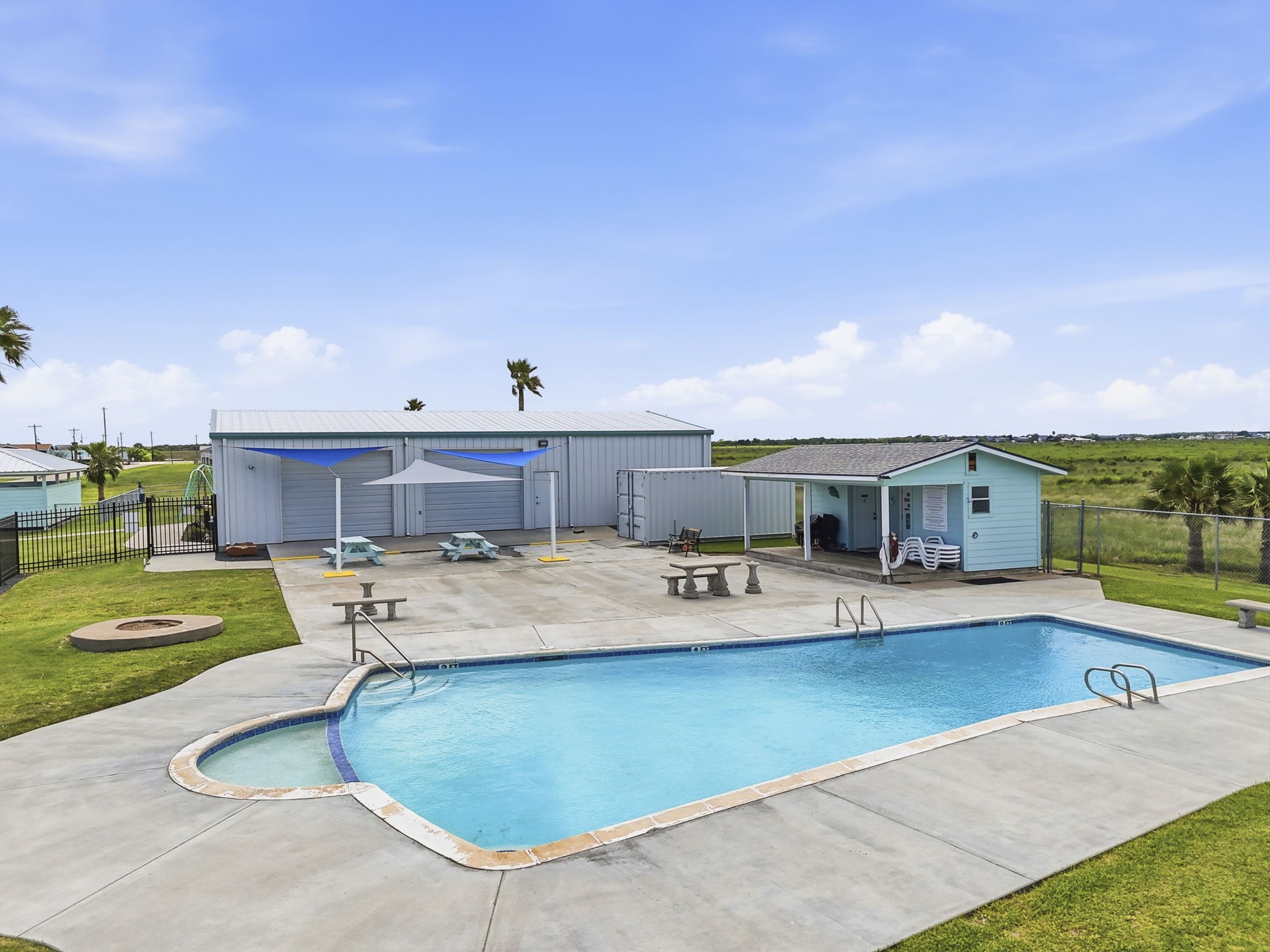 119 Sand Shoals Road Freeport, TX 77541 - Photo 28 of 34 Hide-A-Way on the Gulf community pool — in-ground pool with concrete sun deck, sail shades over picnic tables, fire pit, and pool house. HOA membership included.