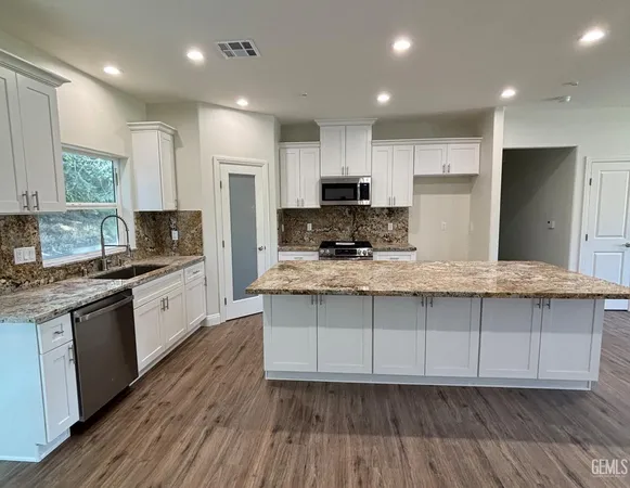 a kitchen with kitchen island granite countertop a sink cabinets and stainless steel appliances