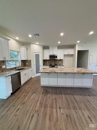 a large kitchen with stainless steel appliances granite countertop a stove a sink dishwasher and a oven with cabinets