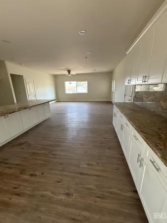 a view of a kitchen with kitchen island a sink wooden floor and black appliances
