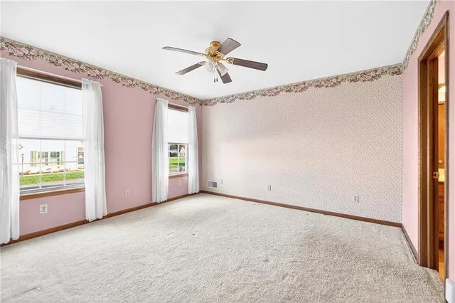 an empty room with windows and fan