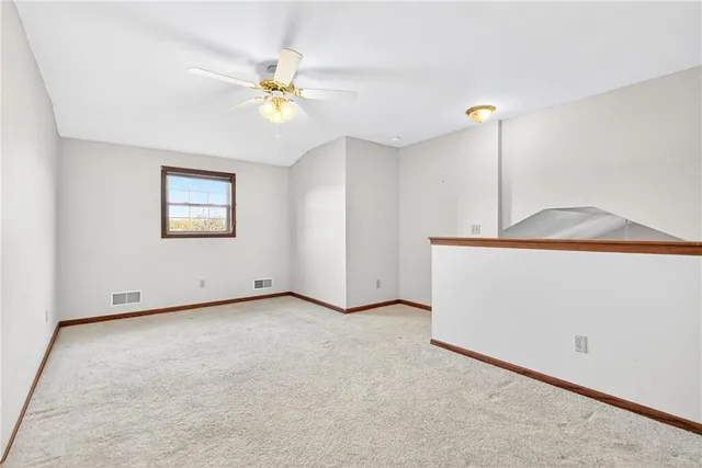 an empty room with chandelier fan and windows