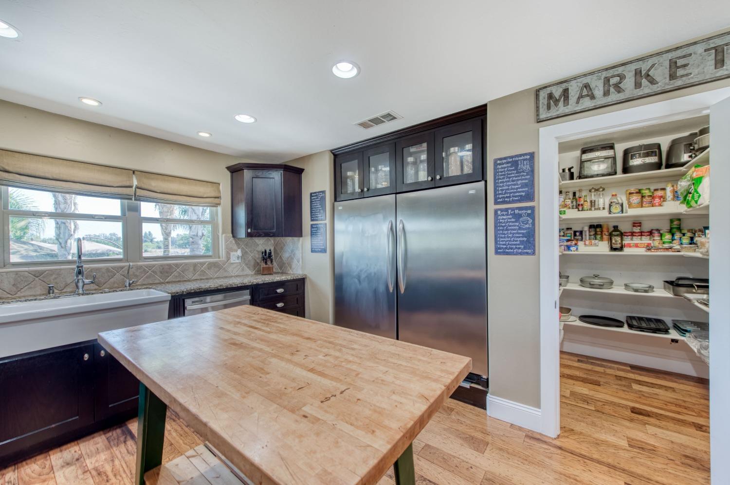 5588 North McCall Avenue Clovis, CA 93619 - Photo 23 of 77 a kitchen with stainless steel appliances granite countertop a refrigerator a sink dishwasher a stove and a dining table with wooden floor