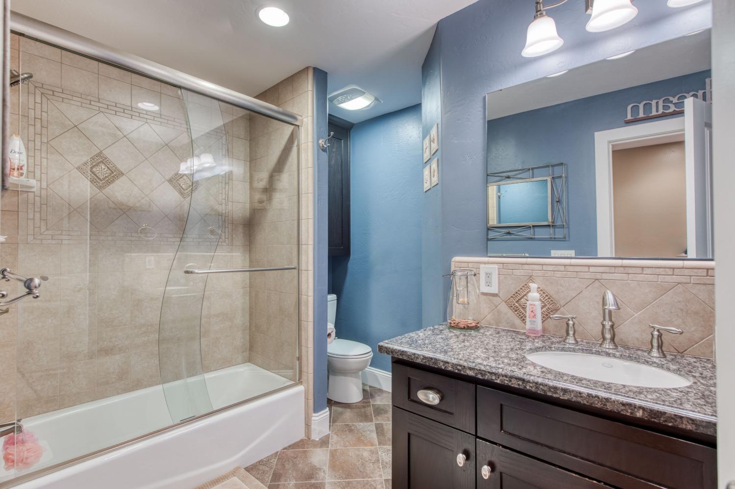 5588 North McCall Avenue Clovis, CA 93619 - Photo 29 of 77 a bathroom with a granite countertop sink a mirror and a bathtub