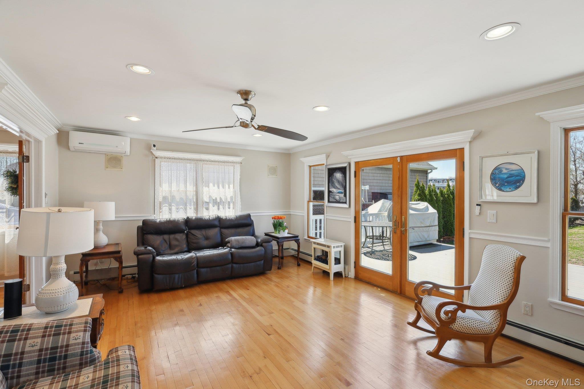230 West Islip Road West Islip, NY 11795 - Photo 11 of 50 Living room with ornamental molding, a wall mounted AC, baseboard heating, light wood finished floors, and french doors
