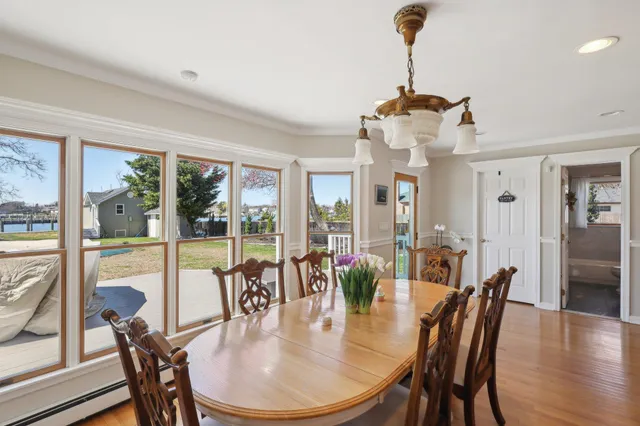 a dining room with wooden floor a chandelier a glass table and chairs