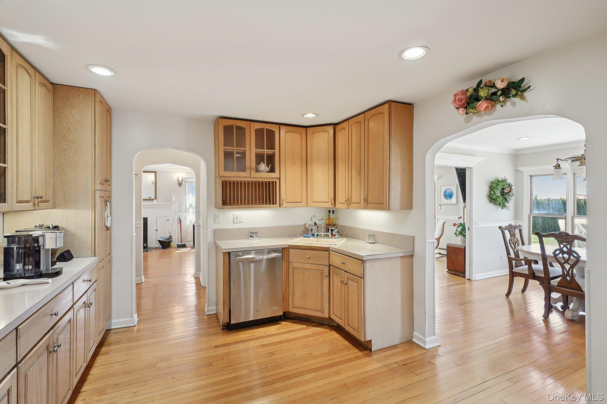 230 West Islip Road West Islip, NY 11795 - Photo 15 of 50 Kitchen featuring glass insert cabinets, arched walkways, light countertops, light wood-type flooring, and stainless steel dishwasher