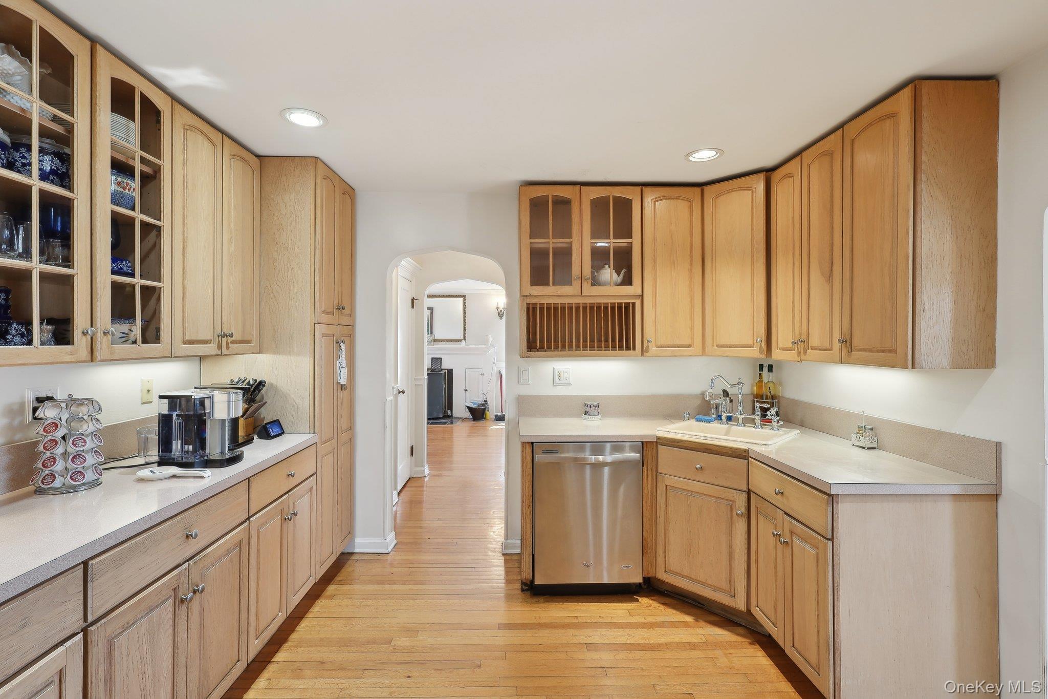 230 West Islip Road West Islip, NY 11795 - Photo 18 of 50 Kitchen featuring glass insert cabinets, light wood-style floors, arched walkways, dishwasher, and a sink