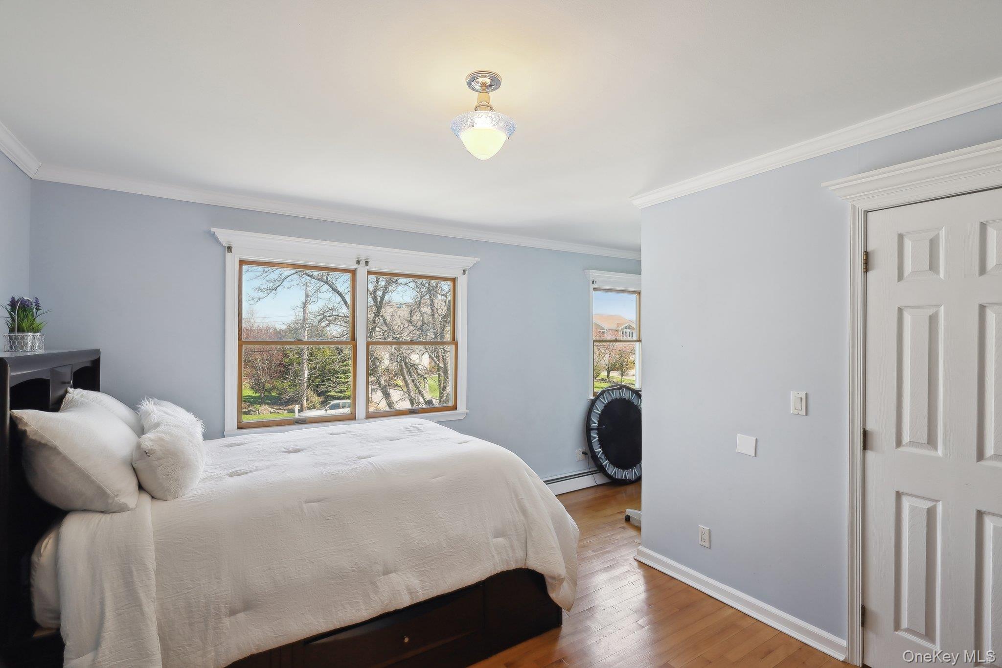 230 West Islip Road West Islip, NY 11795 - Photo 24 of 50 Bedroom featuring a baseboard heating unit, baseboards, crown molding, and wood finished floors