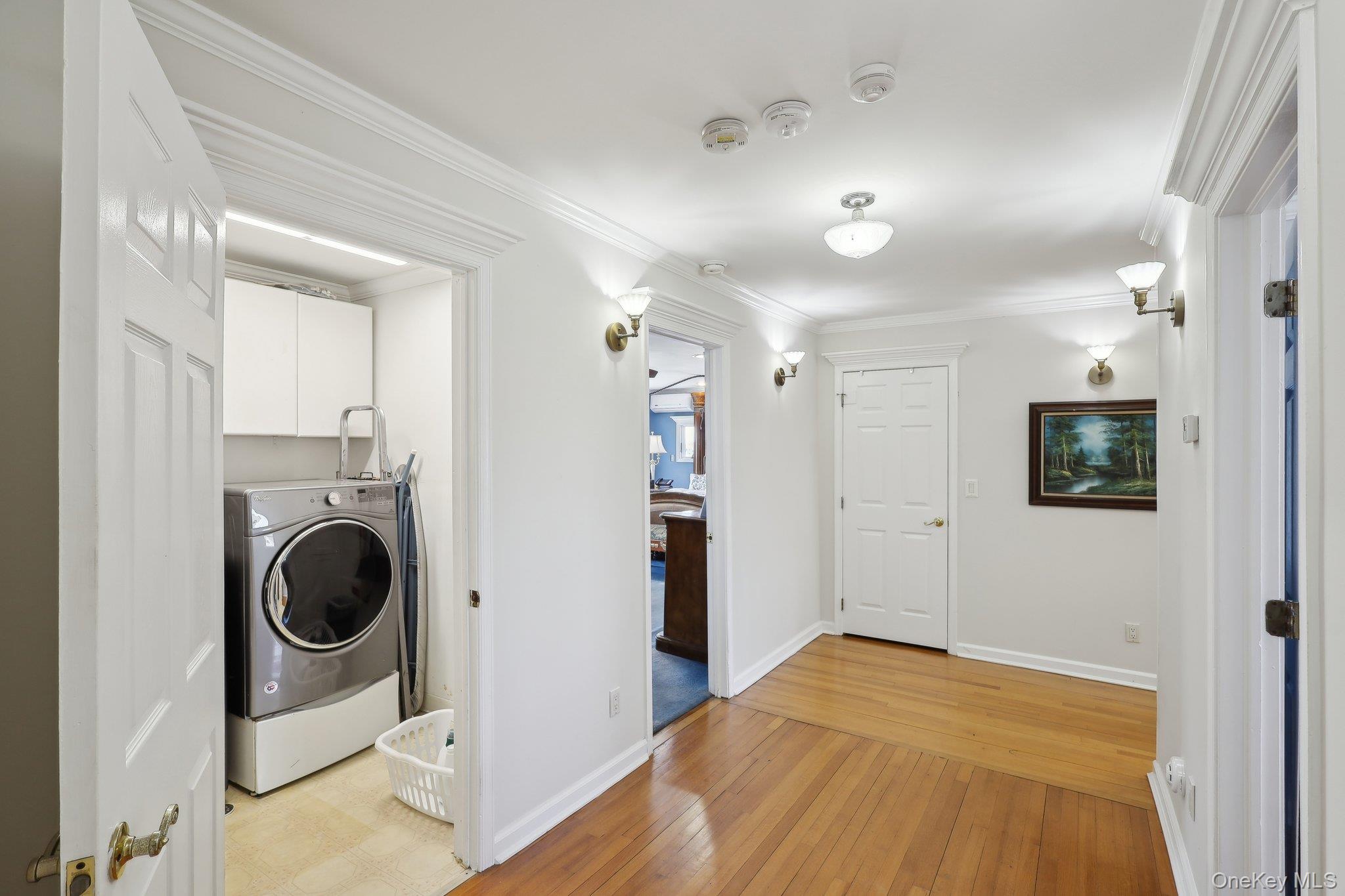230 West Islip Road West Islip, NY 11795 - Photo 32 of 50 Washroom with crown molding, washer / dryer, light wood finished floors, baseboards, and cabinet space