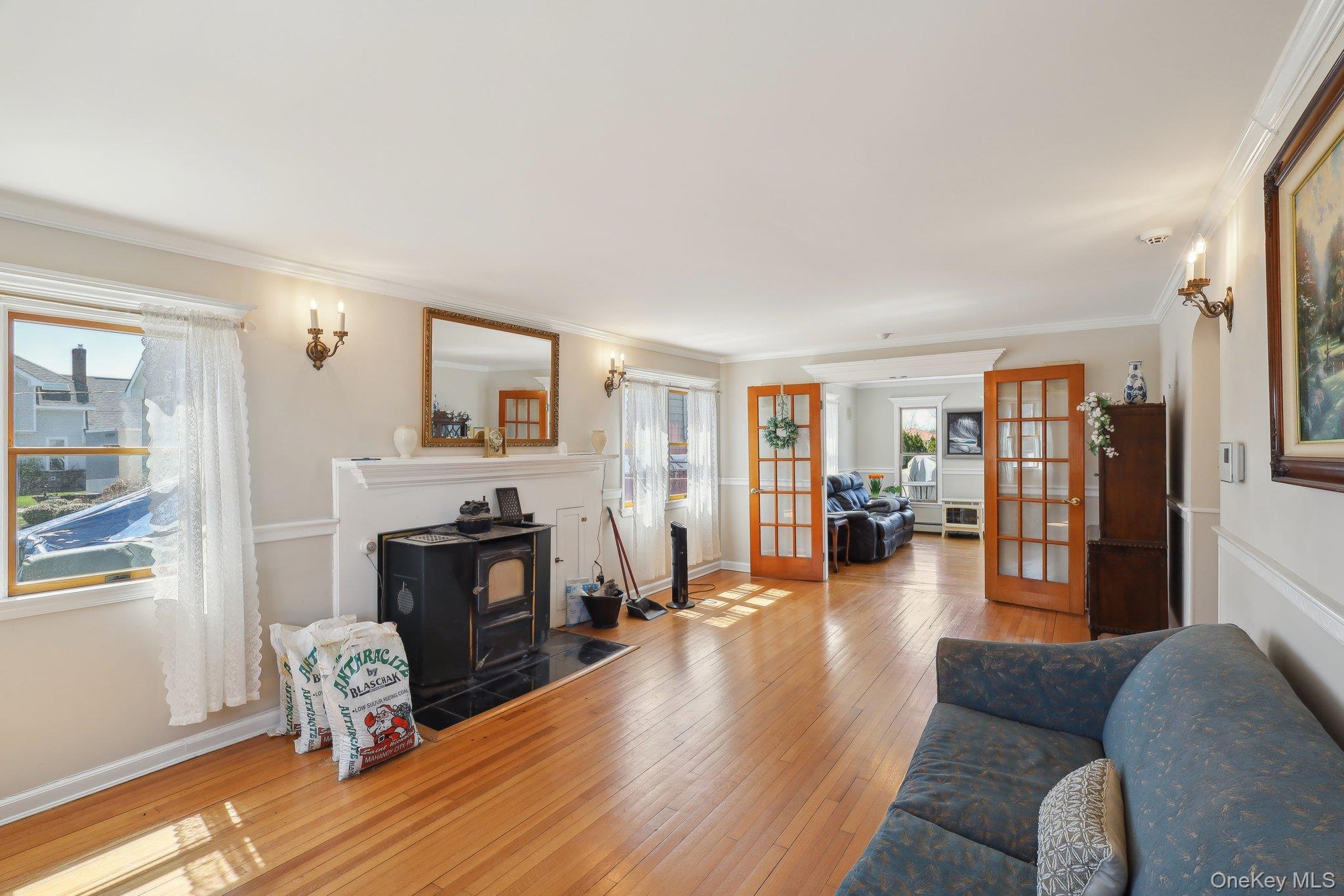 230 West Islip Road West Islip, NY 11795 - Photo 9 of 50 Living area with ornamental molding, wood-type flooring, a wood stove, and french doors