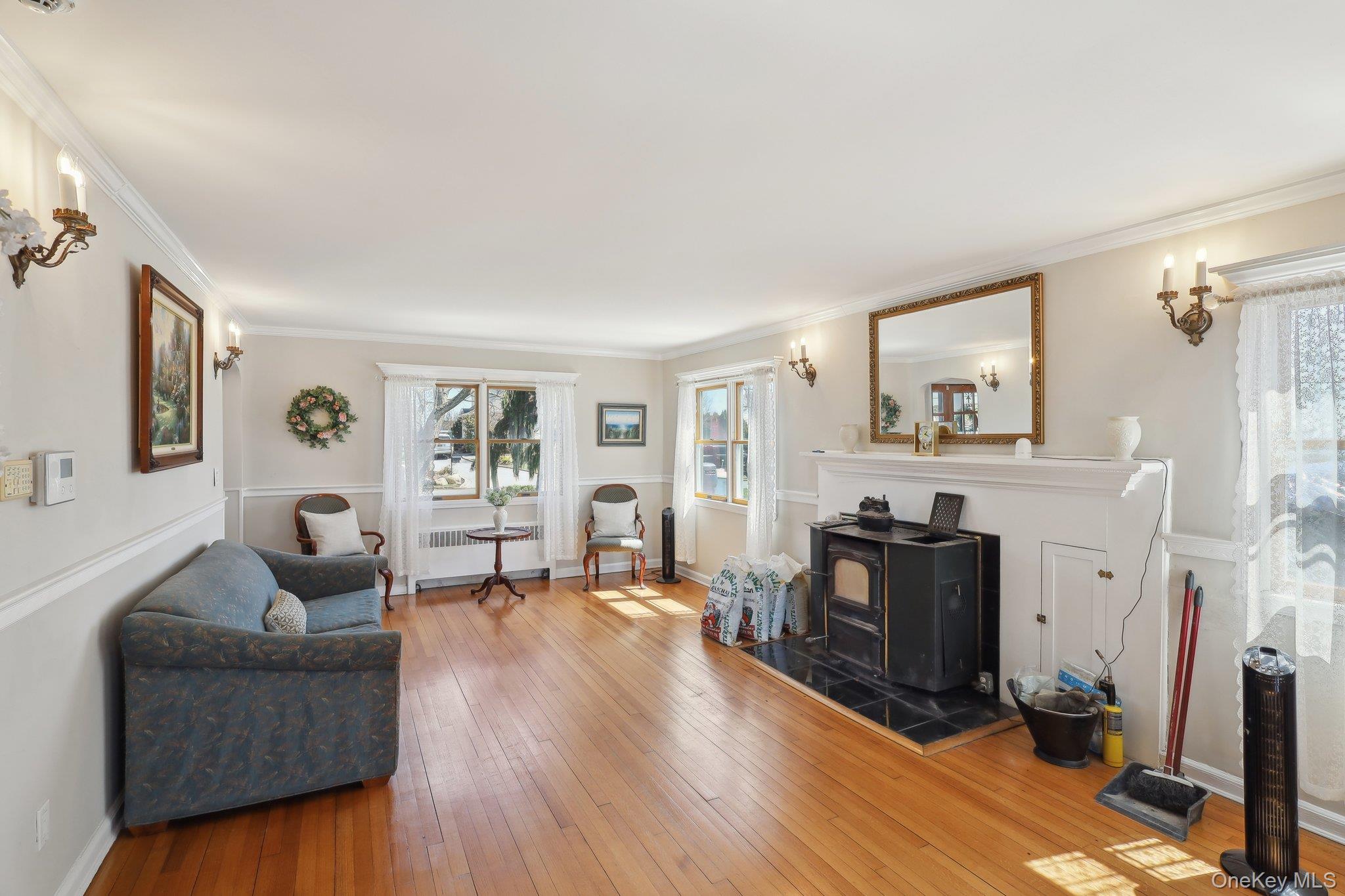 230 West Islip Road West Islip, NY 11795 - Photo 10 of 50 Living room featuring baseboards, ornamental molding, radiator heating unit, a wood stove, and hardwood / wood-style floors