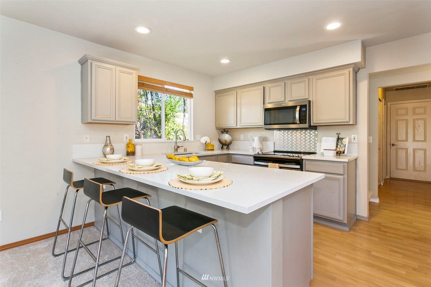 18487 Rainier View Road Southeast Monroe, WA 98272 - Photo 4 of 19 a kitchen with a sink a stove a refrigerator and a dining table with wooden floor
