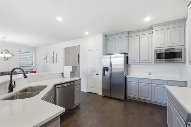 a kitchen with stainless steel appliances granite countertop a refrigerator a sink a stove a microwave and white cabinets