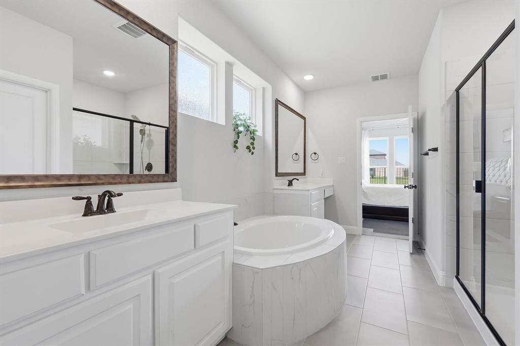 1988 Nottingham Place Allen, TX 75013 - Photo 23 of 40 Bathroom with two vanities, a garden tub, light tile patterned floors, connected bathroom, and a shower stall