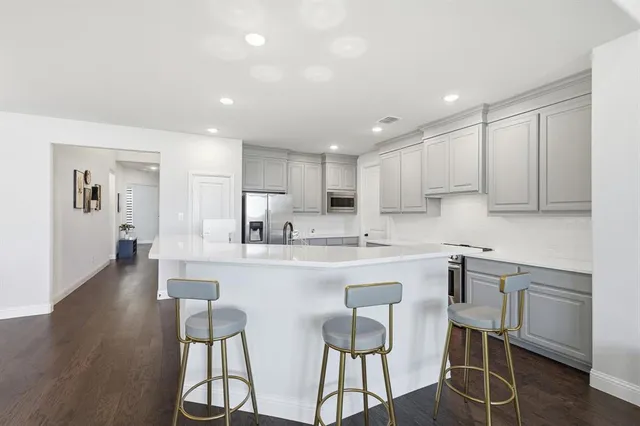 a kitchen with stainless steel appliances granite countertop a table chairs sink and cabinets