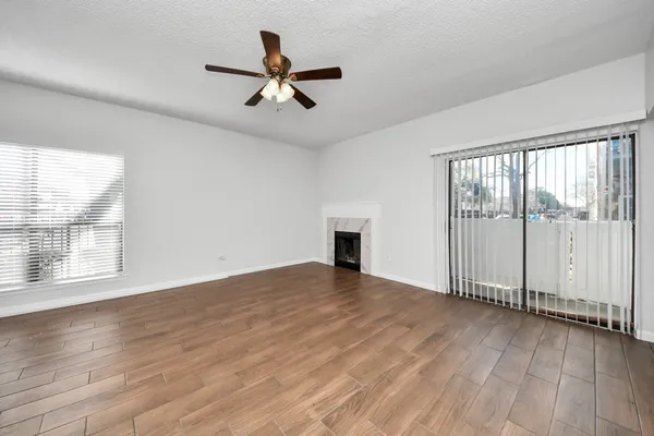 an empty room with wooden floor and ceiling fan