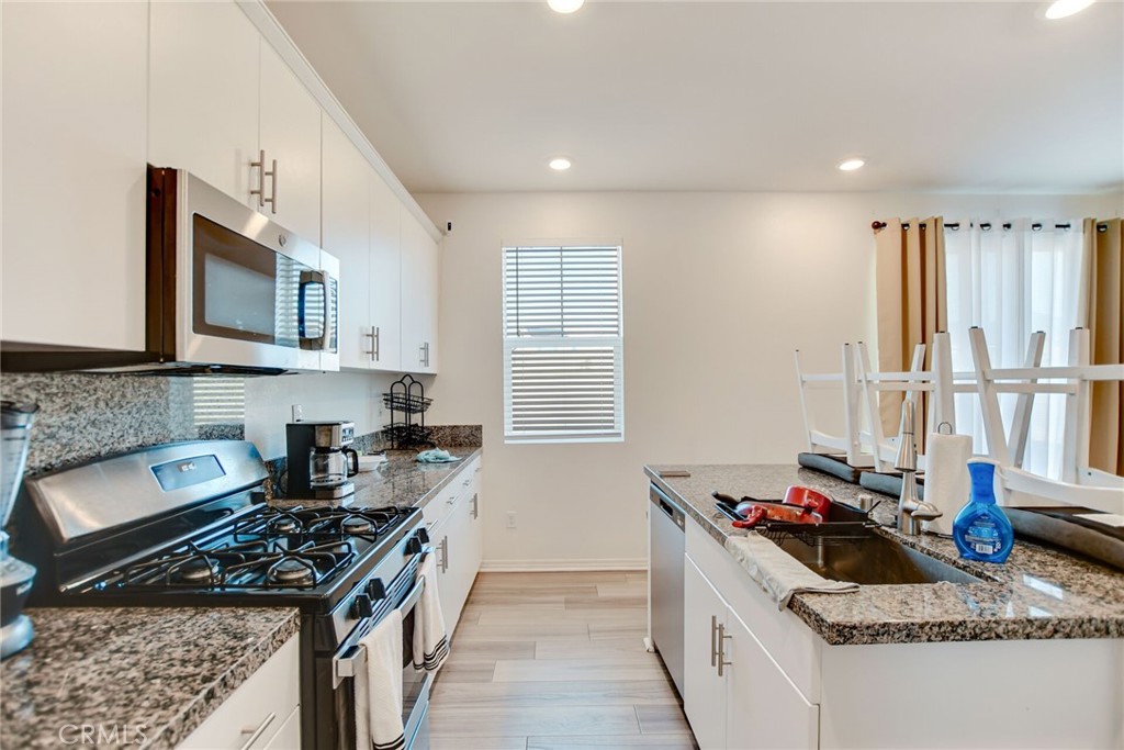 2526 Gunner Ridge Way Rialto, CA 92377 - Photo 19 of 33 a kitchen with granite countertop a stove and a sink