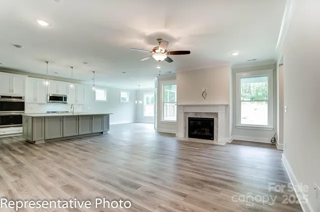 a view of a kitchen with a fireplace a ceiling fan and wooden floor