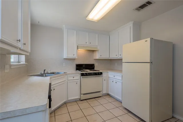 a kitchen with a sink a stove a refrigerator and white cabinets
