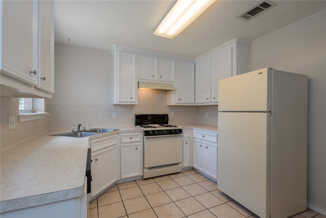 2402 Jaguar Court Bryan, TX 77807 - Photo 12 of 19 a kitchen with a sink a stove a refrigerator and white cabinets