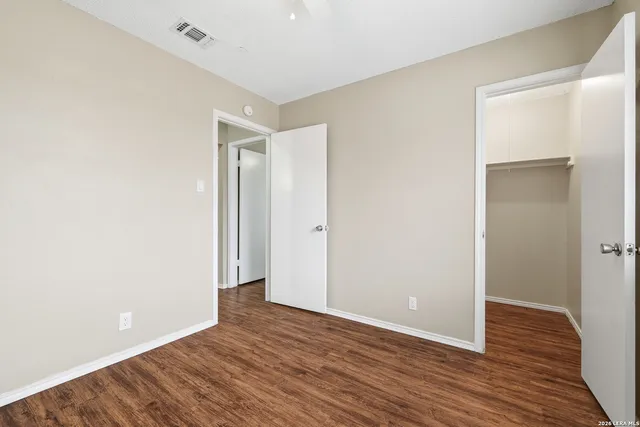 a view of an empty room with wooden floor and closet