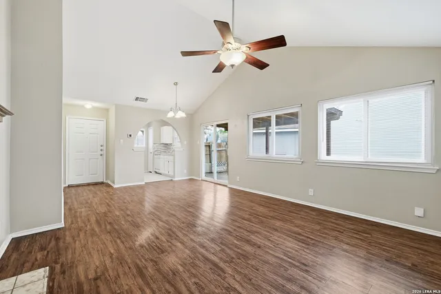 a view of an empty room with wooden floor and a window