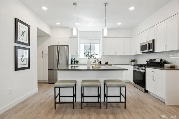 a kitchen with stainless steel appliances granite countertop a dining table chairs refrigerator and sink