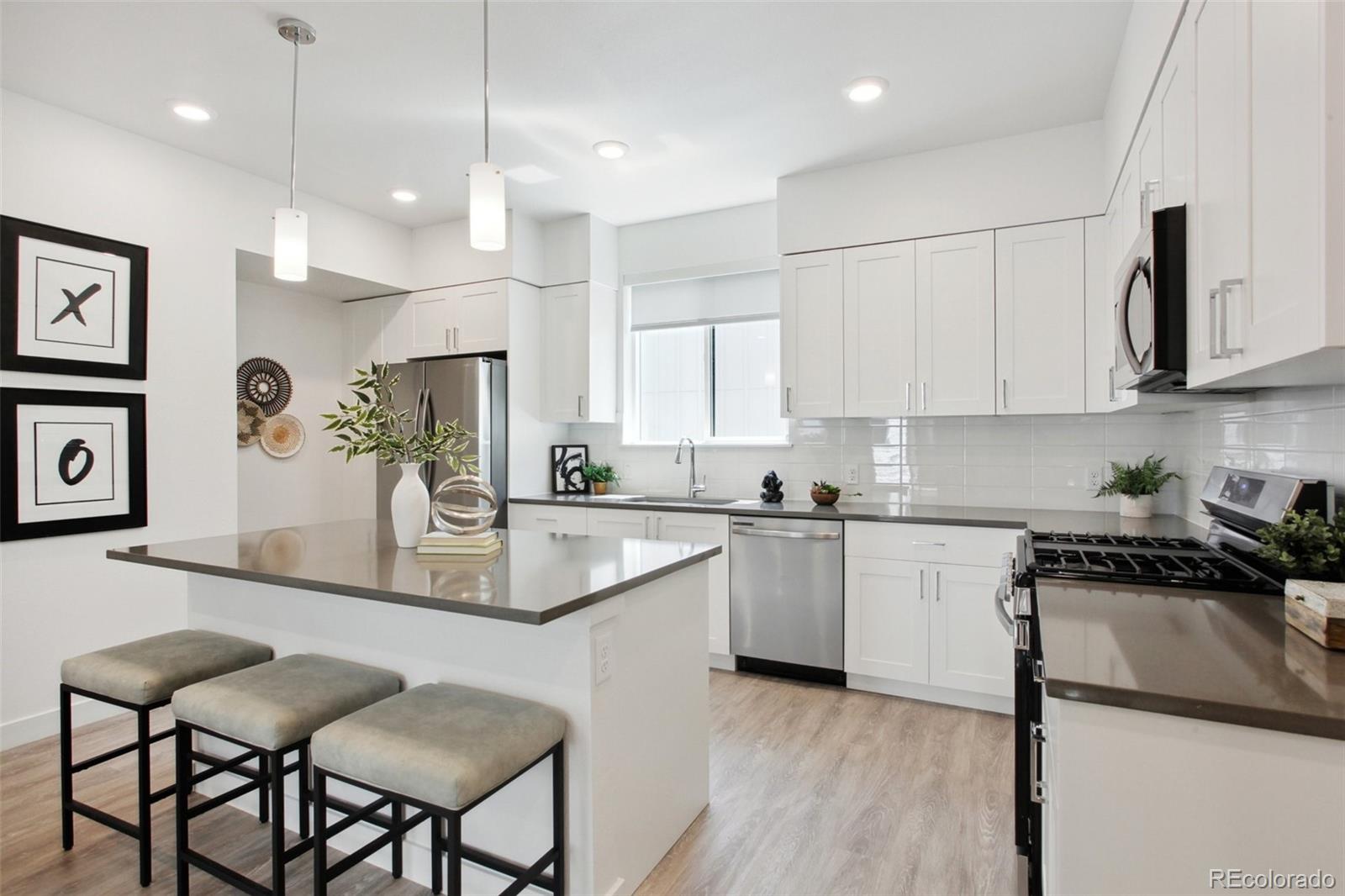 8705 Ralston Road Arvada, CO 80002 - Photo 2 of 16 a kitchen with kitchen island granite countertop a stove a sink a refrigerator and white cabinets with wooden floor