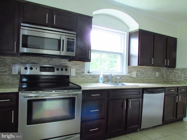 a kitchen with granite countertop a stove microwave and sink